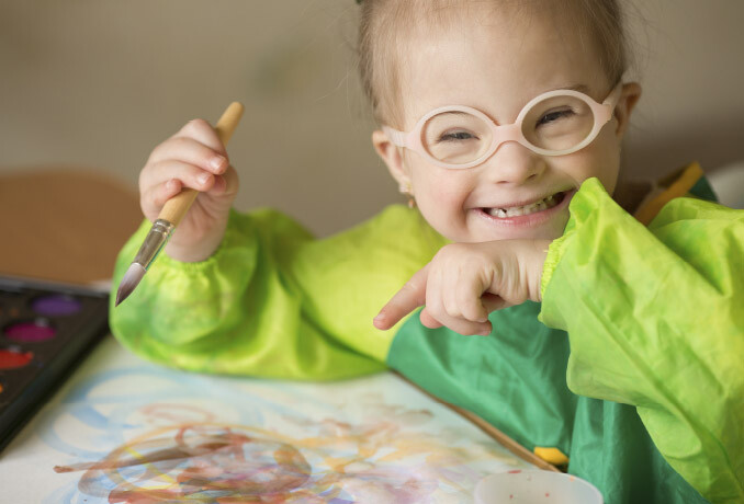 Little girl with glasses smiling while painting
